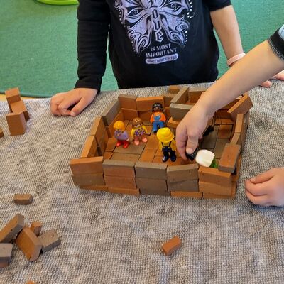 Kinder spielen mit Playmobilfiguren im selbstgebauten Ziegelsteinhaus