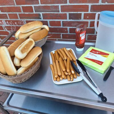 Das Bild zeigt Hotdogs mit Brötchen auf Servierwagen.