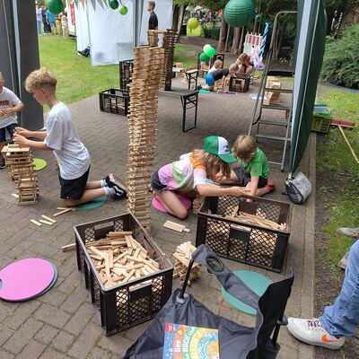 Das Bild zeigt Kinder, die mit Holzbausteinen Türme bauen.