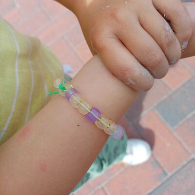 Das Foto zeigt ein Armband mit UV-Perlen, die durch das Sonnenlicht bunt werden.