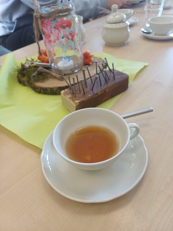 Bild vergr&ouml;&szlig;ern: Das Foto bildet eine mit entkoffinierten Ostfriesentee gefüllten Tasse mit Unterteller und Igeltischdekoration ab.