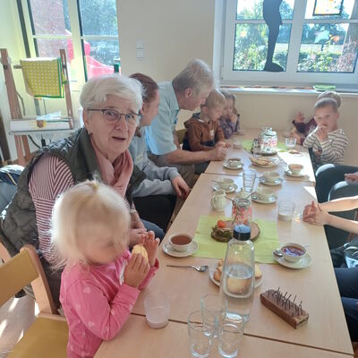 Das Bild zeigt Kinder und Senioren vom Seniorenbeirat Uplengen zusammen am Tisch bei einer gemeinsamen Teestunde.