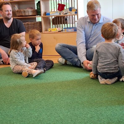 Das Foto zeigt den CDU-Politiker Ulf Thiele mit Kindern im Sitzkreis.