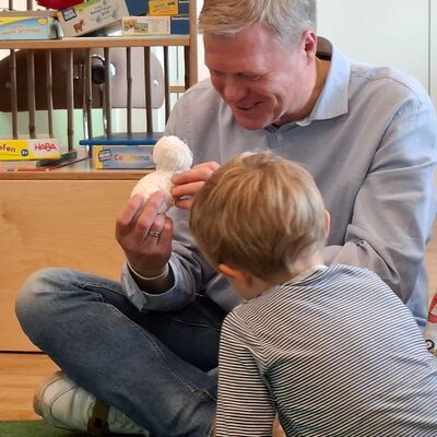 Das Foto zeigt Ulf Thiele (CDU) wie er Kontakt zu den Kindern aufnimmt und ein Kuscheltier betrachtet, das ihm zuvor ein Kind gab.