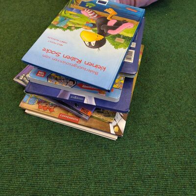 Bild vergr&ouml;&szlig;ern: Das Foto zeigt einen Bücherstapel auf dem Morgenkreisteppich.