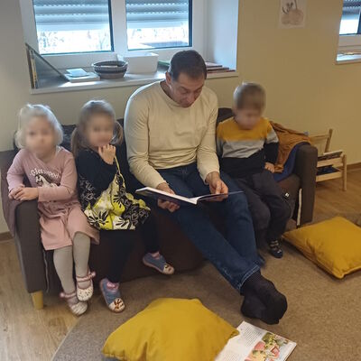 Das Bild zeigt, wie Bürgermeister Heinz Trauernicht auf dem Lesesofa drei Kindern vorliest.