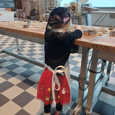Das Foto zeigt ein Mädchen wie es Teig rollt und Plätzchen aussticht.