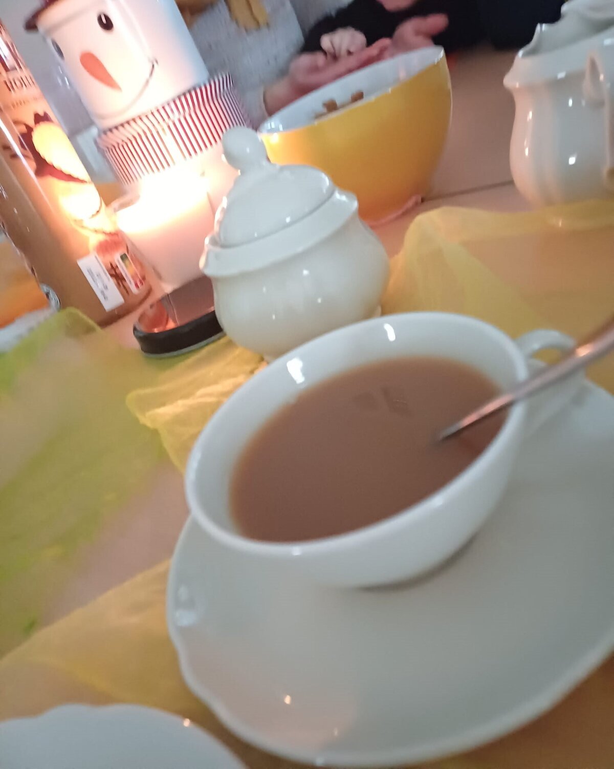 Das Foto zeigt eine gefüllte Tasse mit schwarzem, koffeinfreiem Tee und einer Kerze.