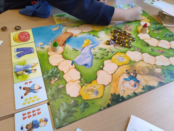Bild vergr&ouml;&szlig;ern: Das Foto zeigt das Spiel "Zahlenzwerge" und ein Kind, das eine Figur auf dem Spielfeld setzt.